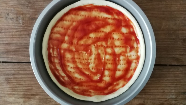 薄底香肠披萨,烘烤5分钟后的披萨底取出，用勺子涂抹一层<a style='color:red;display:inline-block;' href='/shicai/ 699'>番茄酱</a>