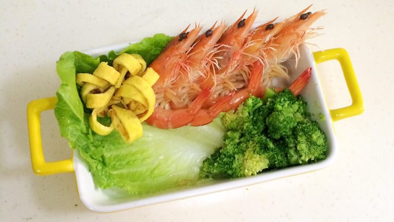 鲜虾时蔬饭团便当,在便当盒或着碗内铺上一张洗净的生菜叶，把煮好的虾依次摆好，西兰花和鸡蛋花朵也放上。