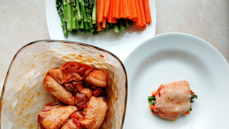 彩蔬酿鸡翅,取出腌制好的鸡翅，把红萝卜丝和芦笋塞进鸡翅里