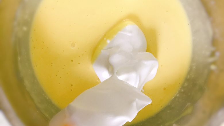 轻乳酪蛋糕（芝士蛋糕）,取1/3蛋白霜加入面粉糊内，用橡皮刮刀翻拌均匀。然后倒回剩下的2/3蛋白霜内混拌均匀。