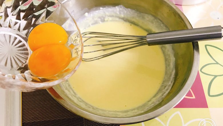 轻乳酪蛋糕（芝士蛋糕）,分次加入蛋黄，用手动打蛋器搅拌均匀。