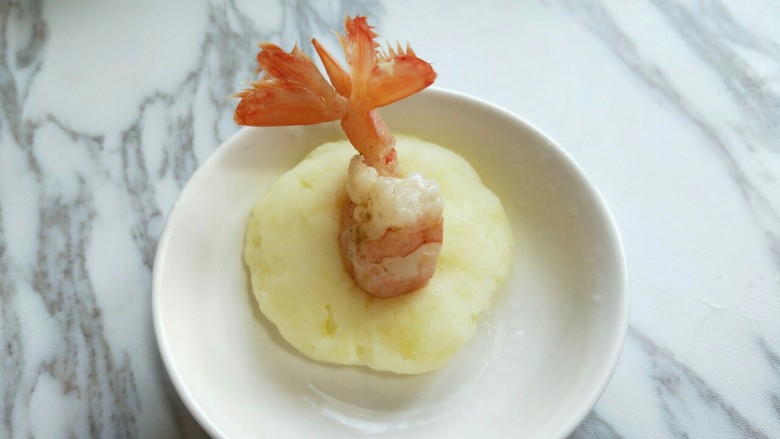 #辅食计划#黄金凤尾虾#煮蛋器版#,取一款土豆泥，用手心压扁，放上腌制好的阿根廷红虾尾。