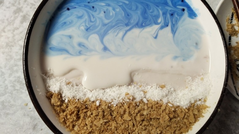 海洋世界~Smoothie bowl,在碗的燕麦这一边底下垫高，低处倒入酸奶，并放入藻蓝蛋白，要分次放入，靠近碗边的多放两次，拉出花和层次。