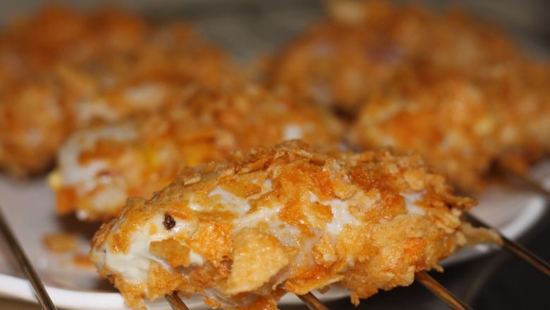 薯片鸡翅,裹满薯片碎的鸡翅有间歇地放入烤架上,烤箱180度预热,烤20分钟即可,中途需翻面一次。