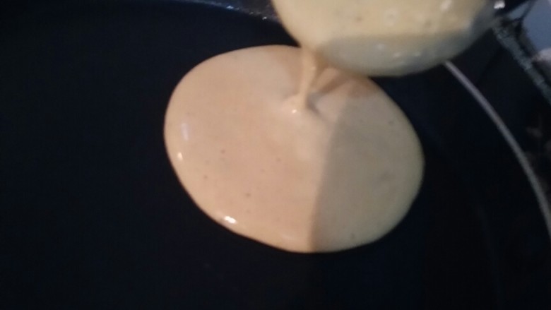 鲜香美味的香蕉松饼,用勺子挖一勺面糊，放入锅中，面糊会自动流动成圆形。