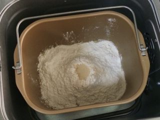 紫薯麻薯夹心软欧,除黄油以外的面包材料都放入面包机内（先液体后粉类的顺序，糖和盐对角放），在面粉中间挖个洞，把酵母粉倒入，启动和面程序。