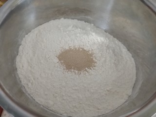 香葱猪肉馅饼,发面：面粉里加酵母（如图），然后把酵母搅拌均匀。