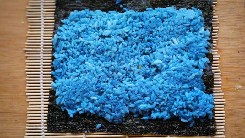 花朵寿司【蓝色系】,海苔上铺米饭，两端各留一段不铺，要是太宽做好的花朵就变成细长形的。