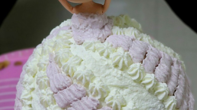 芭比娃娃蛋糕（7寸）,淡奶油分两份，一份加入紫色色素调匀。用104裱花嘴和八齿裱花嘴裱花，做出裙子的图案和褶皱。可自由发挥想象