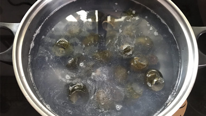 剁椒田螺酿肉,锅中倒入适量清水煮开，把田螺放入锅中。