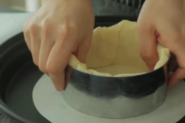 流心芝士挞,饼干面团擀至2-5mm的厚度，裁成8寸圆形大小，填入4寸慕斯圈模中，尽量把折角的部分压实。