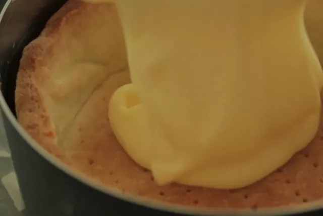 流心芝士挞,将完全冷却的芝士浆料均匀倒入烤好的饼干挞中，尽量将表面抹平。