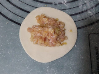 酸菜猪肉饺子,在饺子皮上放入适量的猪肉酸菜馅、按自己习惯捏成饺子状