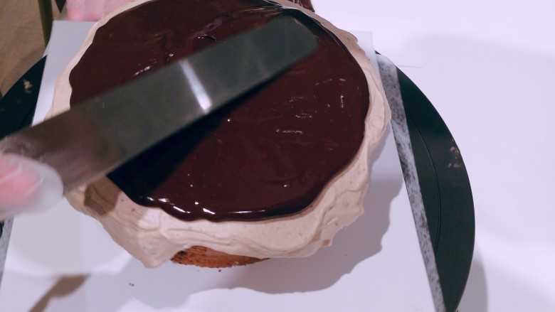 巧克力奶盖蛋糕,制作巧克力酱，将奶油加热至60度，加入融化的黑巧克力，快速搅拌均匀，装入裱花袋中。将巧克力酱挤在蛋糕表面，抹平