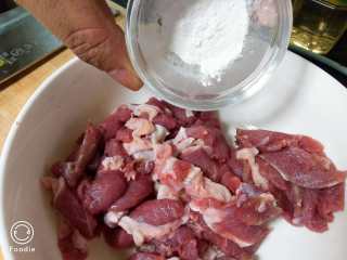 孜然羊肉,将淀粉倒入切好的羊肉片中搅拌 腌制10分钟
