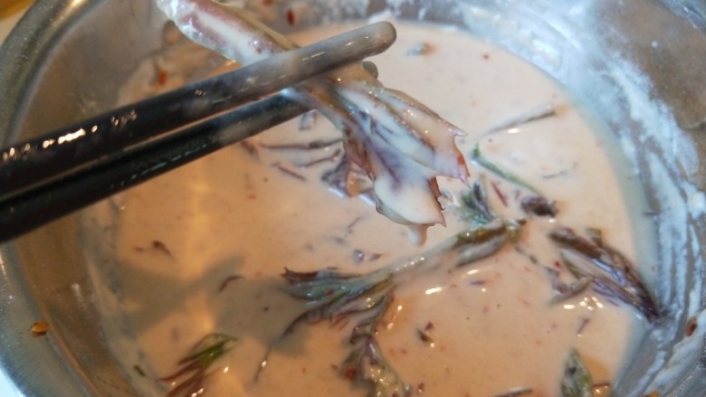 春天特色\炸香椿鱼,用筷子夹头部放入锅中。