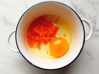 宝宝辅食—香肠馒头抱蛋,一个鸡蛋打入碗内，加入切碎的胡萝卜，搅拌均匀