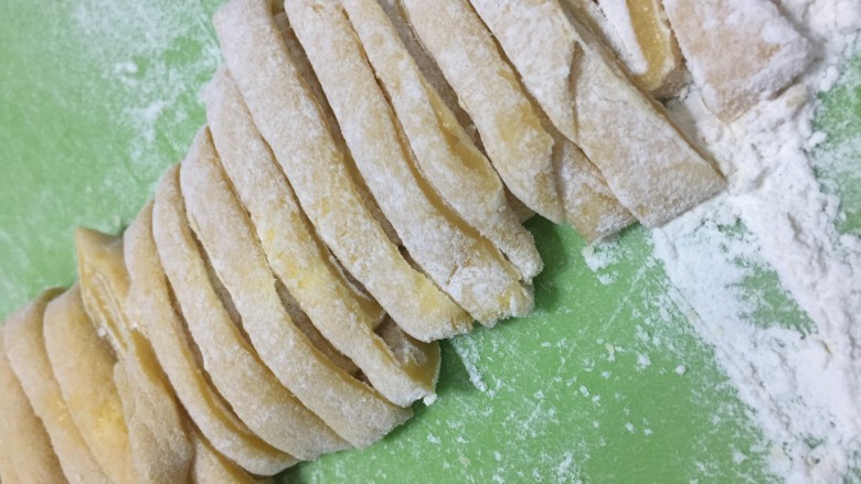 酥脆小麻花（教你做出又酥又脆0失败的麻花）,将面团擀成薄面饼，切成细细的长条，效果和面条一样。
这是切好的样子，稍稍再撒上些干粉防粘。
