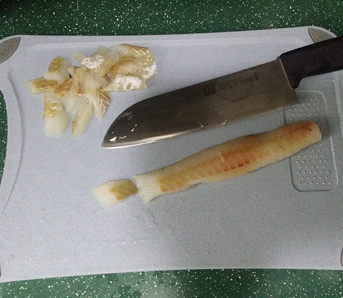 青菜西红柿鳕鱼汤,冲洗干净沥干水分、放至案板上斜切成小块鱼片