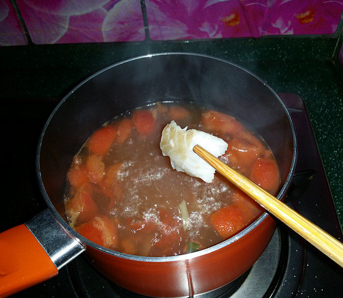 青菜西红柿鳕鱼汤,水开转小火、用筷子拣起鱼片一片一片地汆入锅中