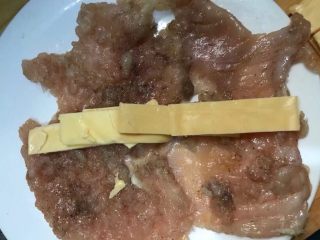 培根芝士鸡肉卷,3.把芝士片切成条状，放在鸡肉中间，然后卷起来。
