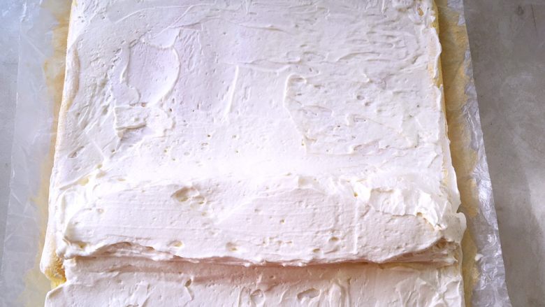 奶油蛋糕卷,冰箱取出淡奶油，用刮棒均匀的涂抹在蛋糕表面，靠近自己的这面多一点