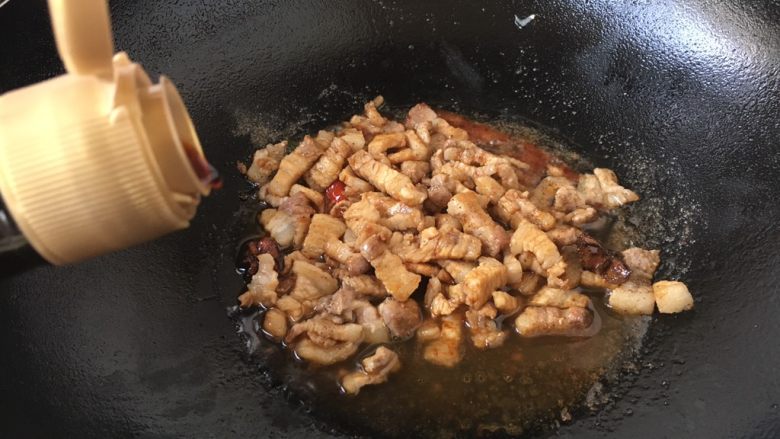 #菌类料理# 黑木耳肉丁蚕豆酥,放入2勺的酱油，翻炒均匀。