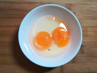 韭苔炒鸡蛋,鸡蛋二个磕入碗里。