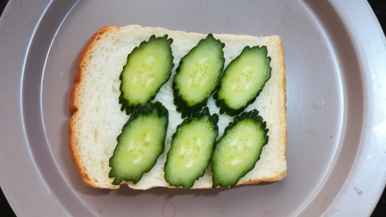 缤纷三明治,取一片烤好的吐司片，放上切片的黄瓜。