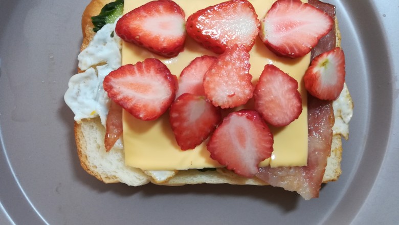 缤纷三明治,放上切好的草莓片，也可以淋一些西红柿酱，沙拉酱或果酱等。
