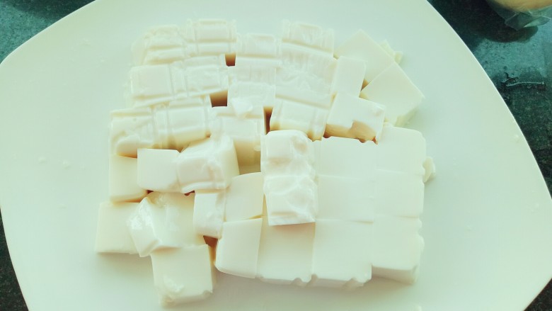 皮蛋豆腐,豆腐切块（把整盒内酯豆腐倒入盘中，直接在盘中用刀切成块。）