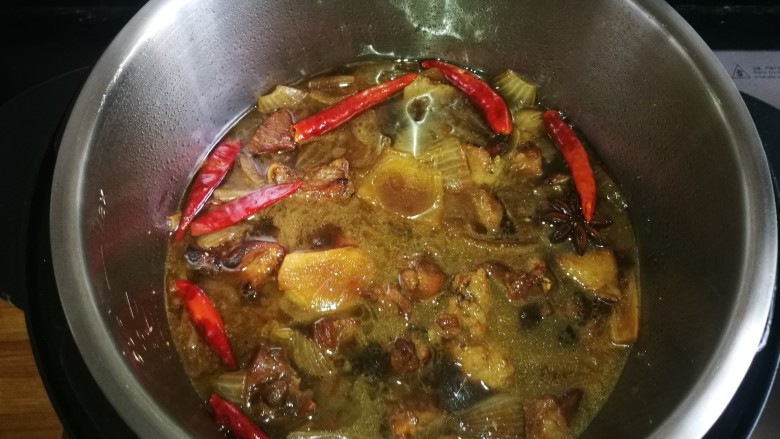 正宗新疆囊包肉,待羊肉变色有些焦黄时加入开水，移至高压锅中，继续加热。