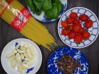 西西里鯷魚番茄義大利麵,將材料備齊。並將小番茄對切成兩半，備用。 
蒜頭去皮後以刀身拍扁，備用。