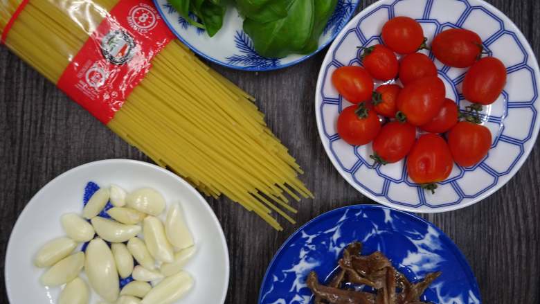 西西里鯷魚番茄義大利麵,將材料備齊。並將小番茄對切成兩半，備用。 
蒜頭去皮後以刀身拍扁，備用。
