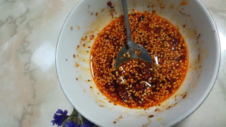 家常冷面,取一个干净的小碗，放辣椒面和芝麻，锅里放油，待油8分热用汤勺盛入碗内，要注意一下一下倒进去，这样才可以把辣椒和芝麻的香味炸出来。