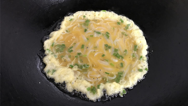 银鱼炒蛋,把搅匀的蛋液倒入锅中。