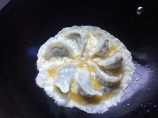 抱蛋煎饺,将蛋液倒入锅中，轻轻晃动锅底，让鸡蛋均匀的包裹饺子。