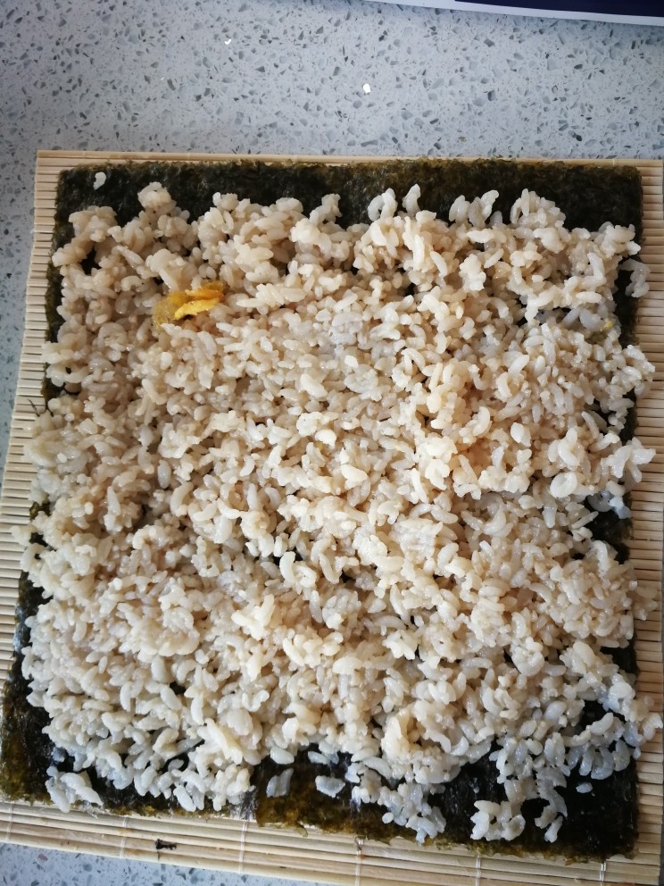 紫菜包饭,铺好米饭，最上面要留出半厘米的空余，防止卷到最后掉出米饭，影响美观。