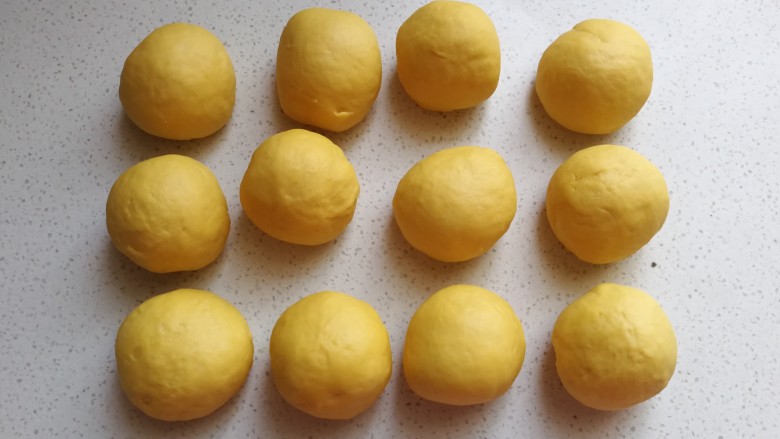 黄金南瓜小方卷,把发酵好的面团取出挤压排气，然后分成均匀的12个小剂子滚圆盖保鲜膜静置10~15分钟
