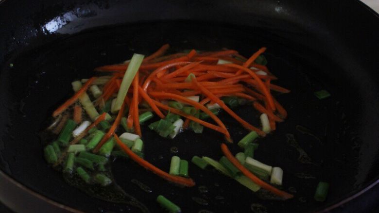 油条韭黄炒墨鱼,8.热锅热油先下入葱姜蒜和胡萝卜丝炒出香味。
