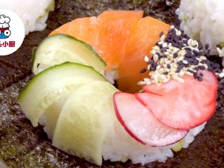 零难度寿司甜甜圈,米饭表面依次铺上三文鱼片、黄瓜片、樱桃萝卜片、熟芝麻