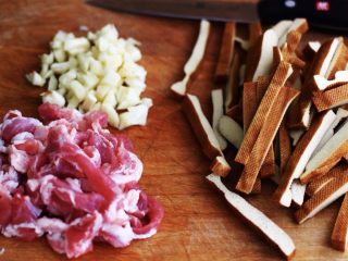 蚝油茼蒿肉丝豆干小炒,把猪肉和豆干用刀切成条状、大蒜切成碎末