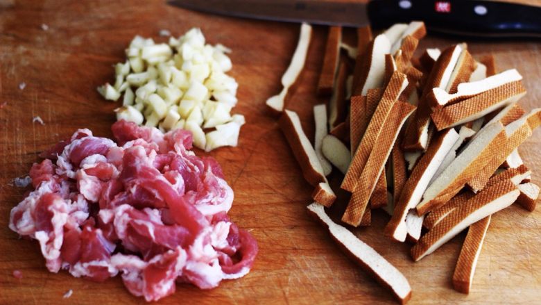 蚝油茼蒿肉丝豆干小炒,把猪肉和豆干用刀切成条状、大蒜切成碎末