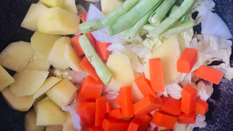 丰收菜,待肉半熟，加入土豆、白菜、豆角、胡萝卜，翻炒至微微变色