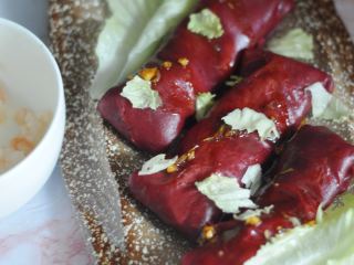 虾仁红米肠粉卷,用微波炉将剩下的虾仁弄熟，和生菜叶一起撕碎，都铺在肠粉卷上，最后将调好的料汁浇在上面。
