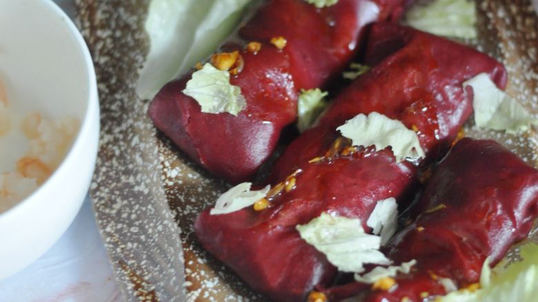 虾仁红米肠粉卷,用微波炉将剩下的虾仁弄熟，和生菜叶一起撕碎，都铺在肠粉卷上，最后将调好的料汁浇在上面。
