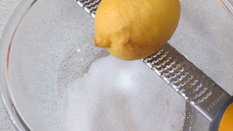 法式小甜点【椰蓉柠檬小方】,制做柠檬酱。将砂糖放入碗中，擦入2 个柠檬皮屑