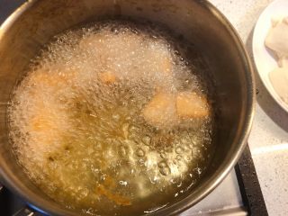 普宁炸豆腐,炸至表面微黄时翻动豆腐，继续炸至两面金黄。