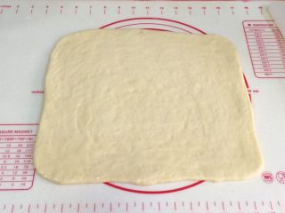 蔓越莓方块小面包,取出冷冻松弛好的面片，继续擀开，刷上一层炼乳。