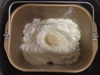 蔓越莓方块小面包,除黄油以外的面包材料都放入面包机内，先液体后粉类的顺序，糖和盐对角放，在面粉中间挖个洞，把酵母粉倒入，启动和面程序。